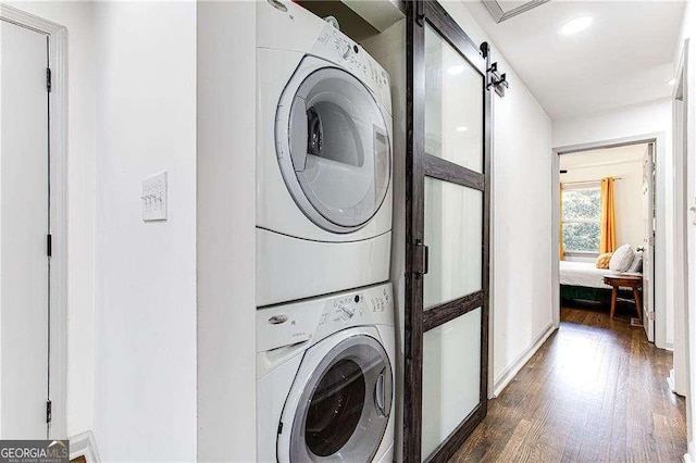 washroom featuring dark wood-style floors, laundry area, and stacked washing maching and dryer