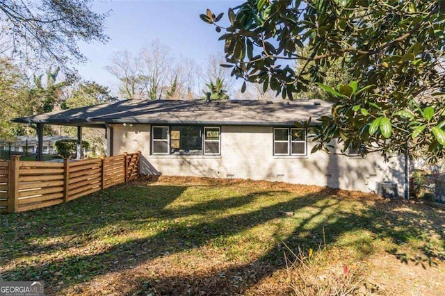 exterior space with crawl space, brick siding, fence, and a lawn