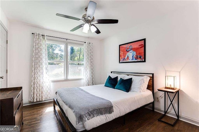 bedroom with dark wood-type flooring, a ceiling fan, and baseboards