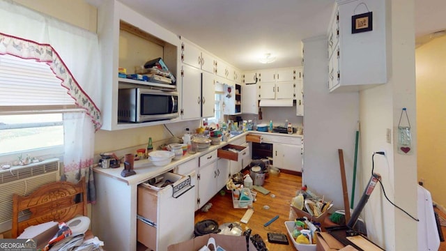 kitchen featuring light wood-style floors, white cabinets, light countertops, and stainless steel microwave