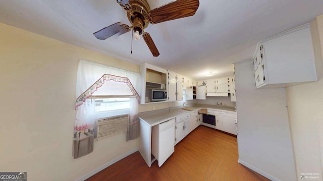 kitchen with wall oven, light wood-style floors, white cabinets, light countertops, and stainless steel microwave