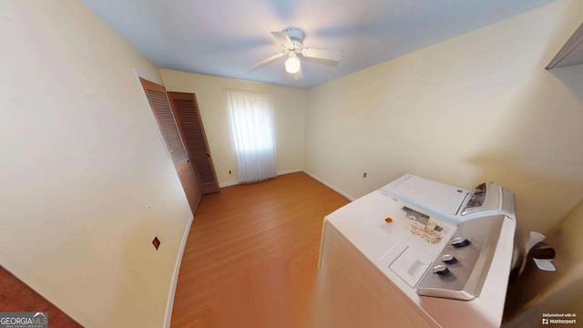 interior space with a ceiling fan, wood finished floors, baseboards, and separate washer and dryer