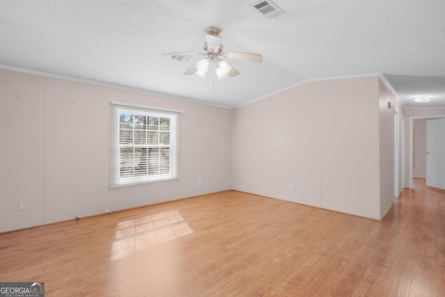 empty room featuring light wood-style floors, a textured ceiling, visible vents, and crown molding