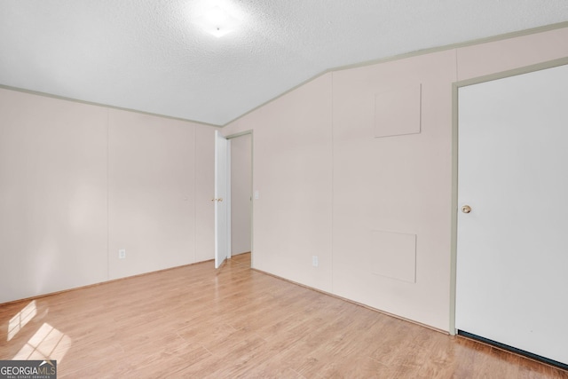 interior space featuring light wood-style floors, lofted ceiling, and a textured ceiling