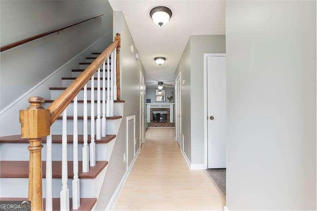 hall with light wood-type flooring, baseboards, and stairs