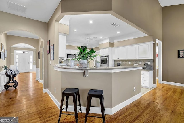 kitchen with stainless steel appliances, a breakfast bar, visible vents, and ceiling fan