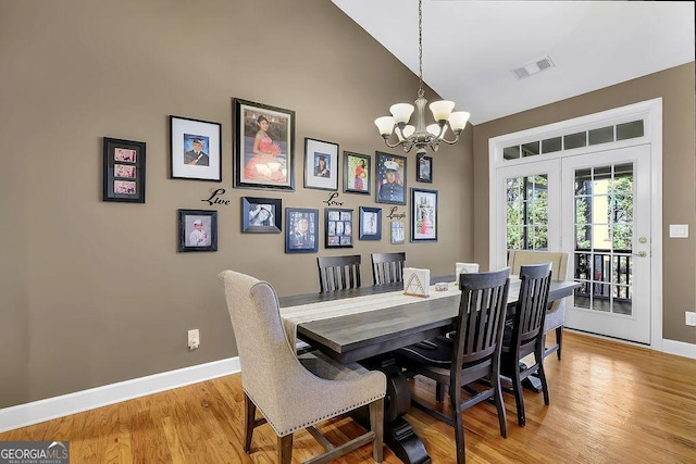 dining space with light wood-type flooring, visible vents, vaulted ceiling, and baseboards