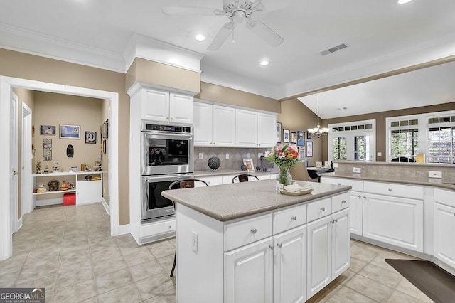 kitchen with a center island, light countertops, visible vents, backsplash, and stainless steel double oven