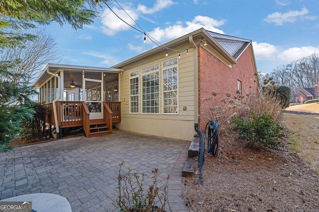 rear view of house featuring brick siding, a patio, a ceiling fan, a sunroom, and a wooden deck