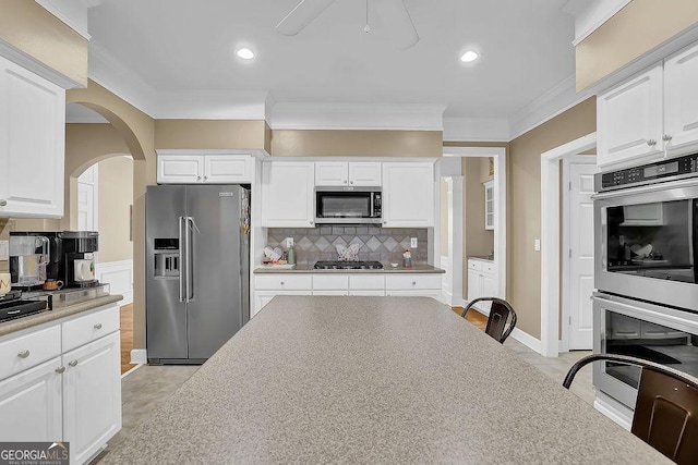 kitchen with white cabinetry, appliances with stainless steel finishes, backsplash, and crown molding