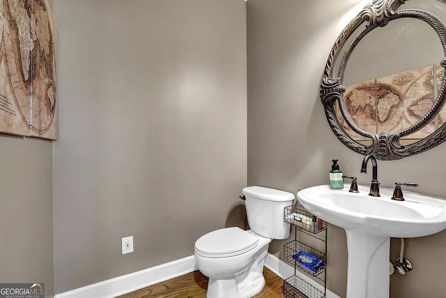 bathroom featuring toilet, baseboards, and wood finished floors