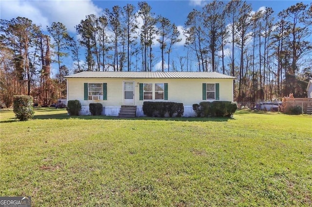 view of front of house featuring entry steps, metal roof, a front lawn, and fence