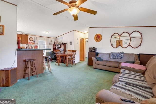 living area featuring lofted ceiling, carpet, ornamental molding, and a ceiling fan