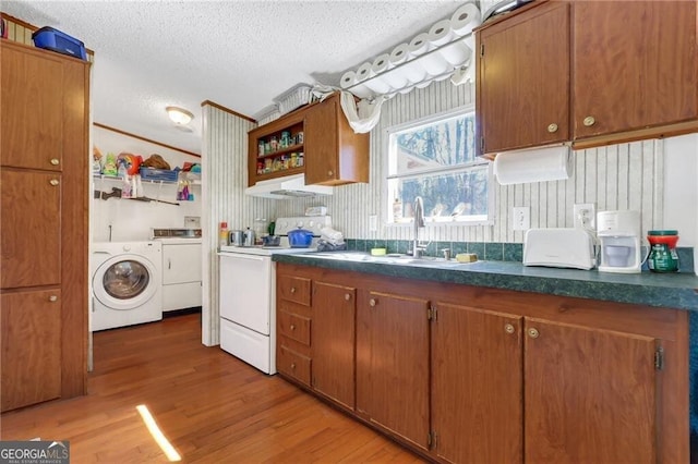 kitchen featuring a textured ceiling, a sink, brown cabinets, white range with electric cooktop, and dark countertops