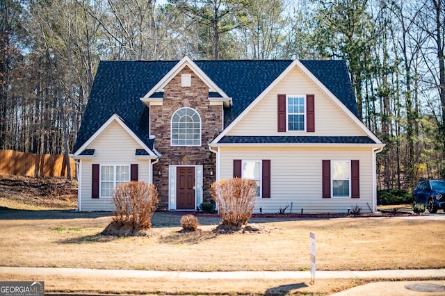 traditional home featuring stone siding, a shingled roof, and a front lawn