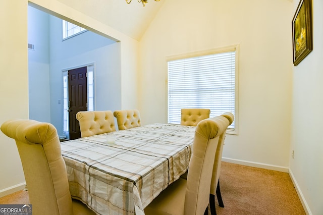 dining room featuring high vaulted ceiling, visible vents, baseboards, and light colored carpet