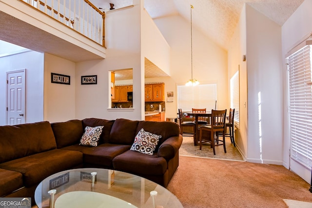 living room with a wealth of natural light, light colored carpet, an inviting chandelier, a textured ceiling, and high vaulted ceiling