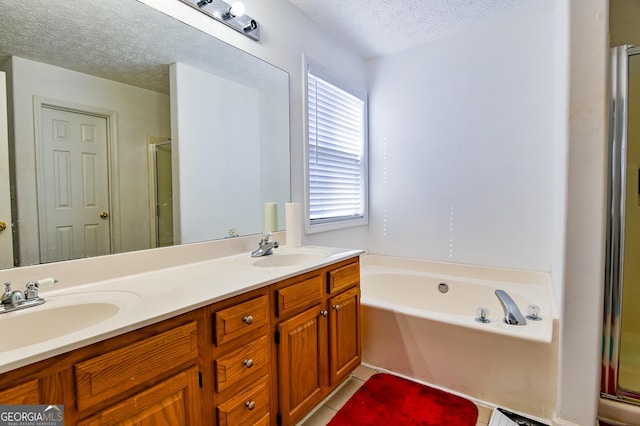 full bathroom with a garden tub, double vanity, a sink, a textured ceiling, and tile patterned floors