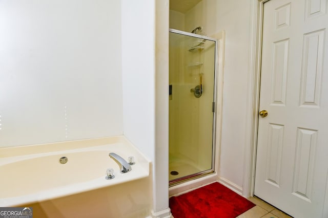 bathroom with a stall shower, tile patterned flooring, and a bath