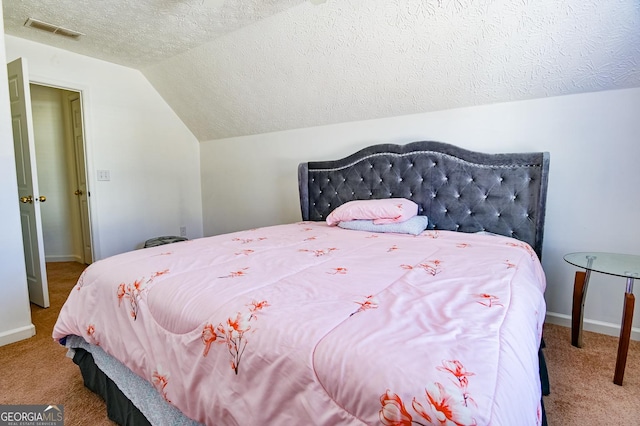 carpeted bedroom with baseboards, visible vents, vaulted ceiling, and a textured ceiling