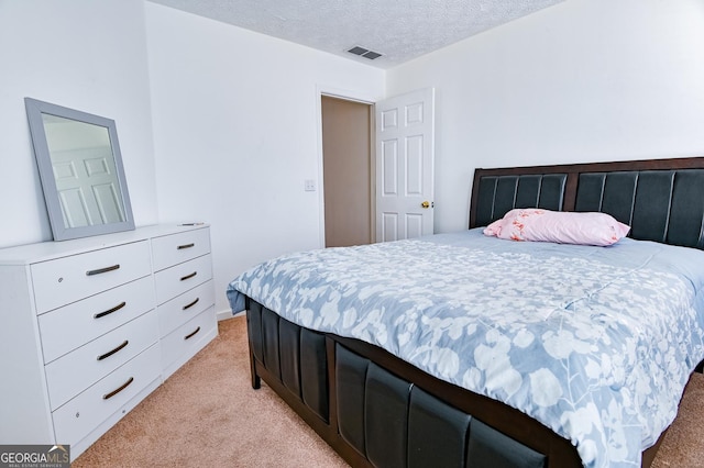 bedroom with light carpet, a textured ceiling, and visible vents