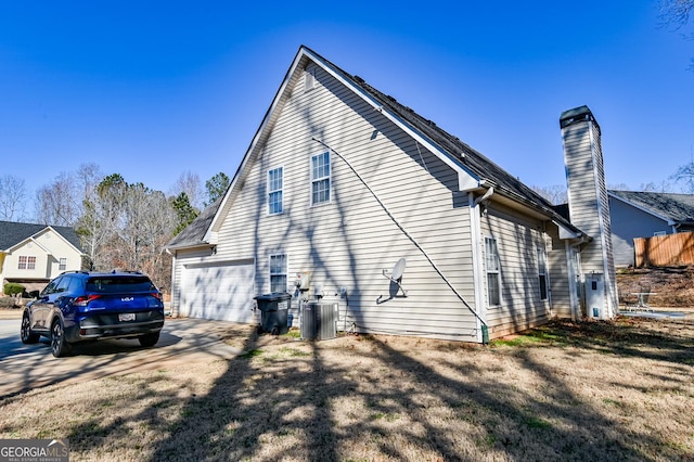 view of side of home featuring driveway, a garage, and central AC unit