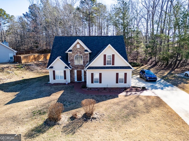 traditional-style house with stone siding, fence, and driveway