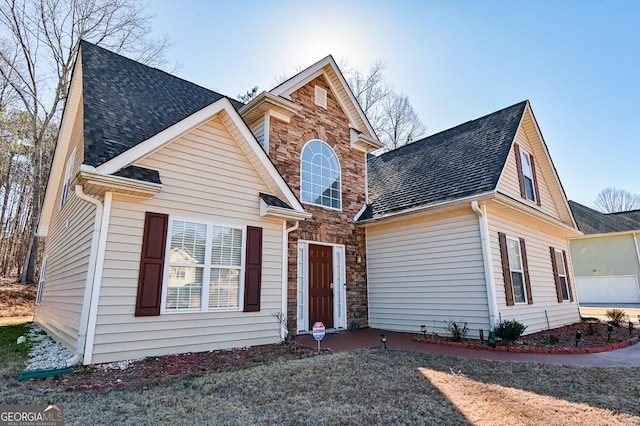 traditional home with stone siding and a shingled roof