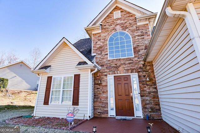 traditional home with stone siding and a shingled roof