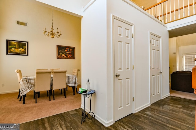 interior space with a towering ceiling, baseboards, visible vents, dark wood finished floors, and an inviting chandelier