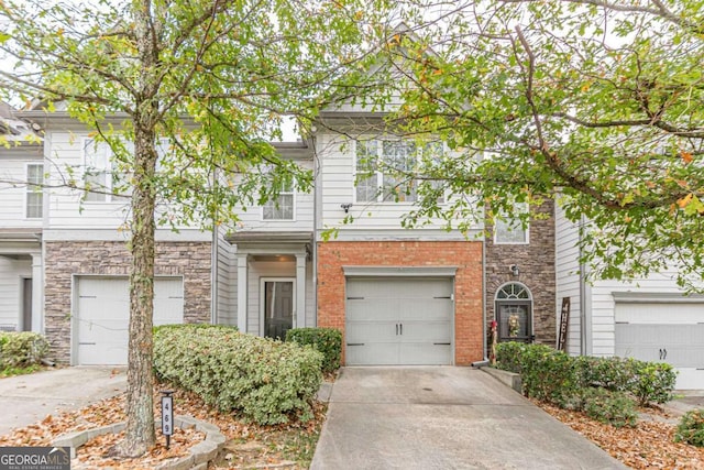 view of property featuring driveway, brick siding, and an attached garage