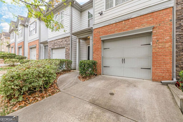 exterior space featuring a garage, brick siding, and driveway