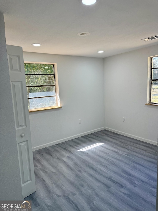 spare room with baseboards, visible vents, a wealth of natural light, and wood finished floors