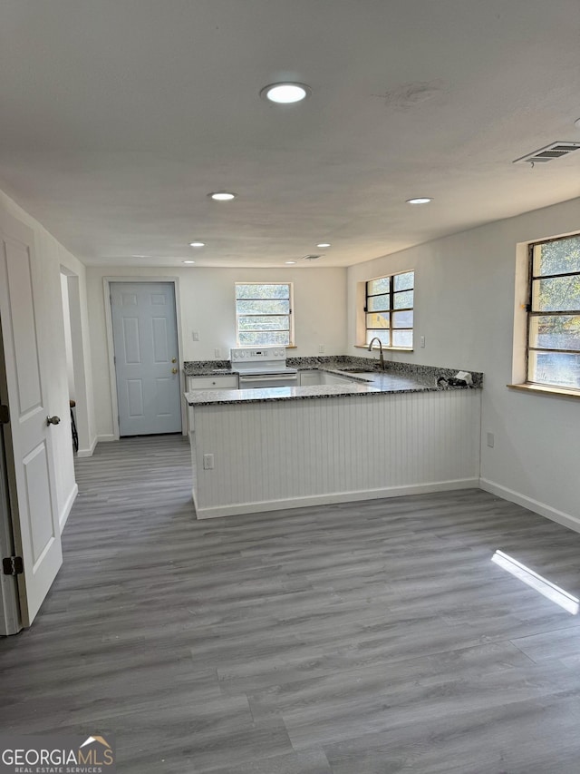 kitchen featuring light wood finished floors, recessed lighting, visible vents, white electric range, and a peninsula