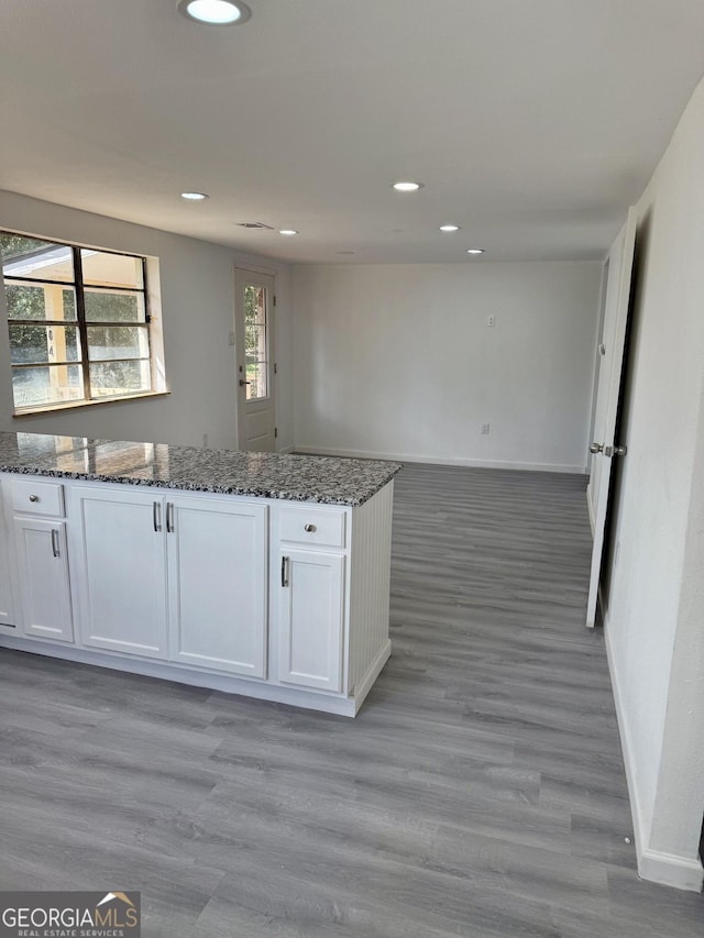 kitchen featuring baseboards, dark stone counters, white cabinets, and open floor plan