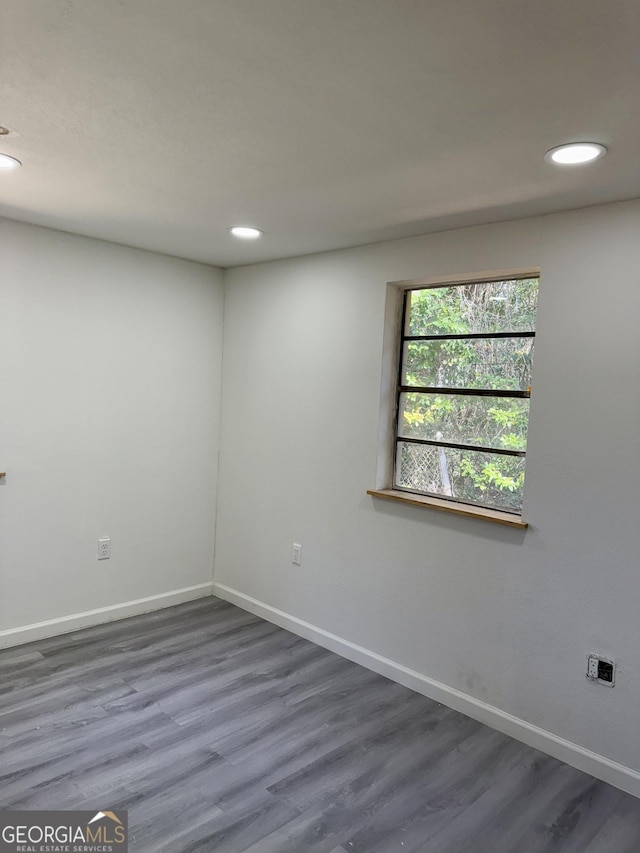 spare room featuring recessed lighting, wood finished floors, and baseboards