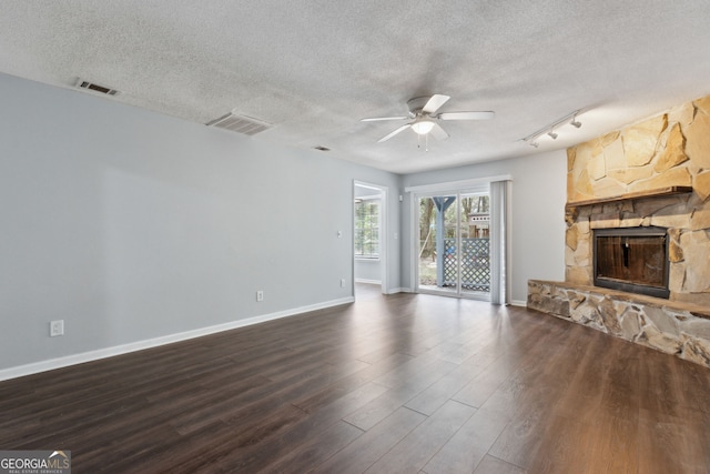 unfurnished living room featuring a textured ceiling, dark wood-type flooring, a fireplace, a ceiling fan, and baseboards