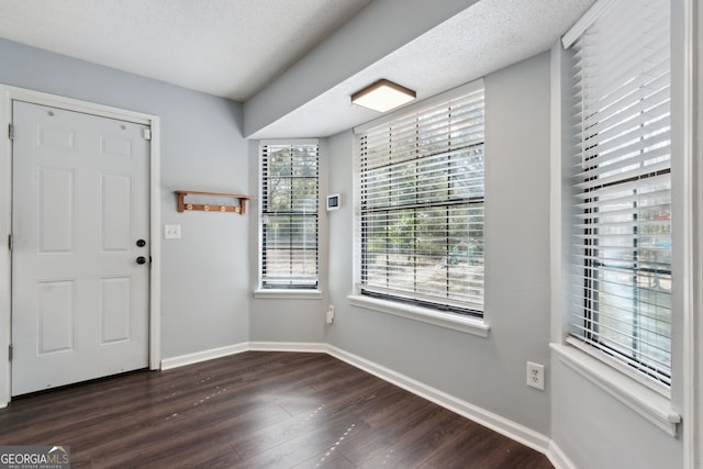 entryway with dark wood-style floors, baseboards, and a textured ceiling