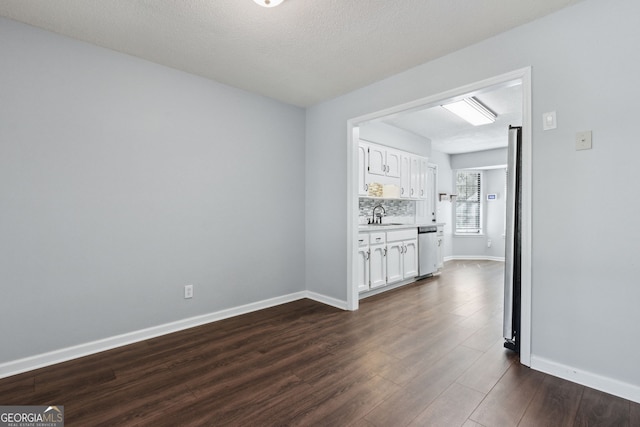 interior space with a textured ceiling, dark wood-style flooring, a sink, and baseboards