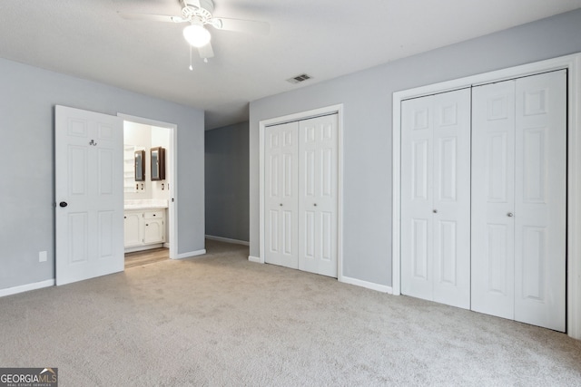 unfurnished bedroom with visible vents, light carpet, baseboards, and two closets