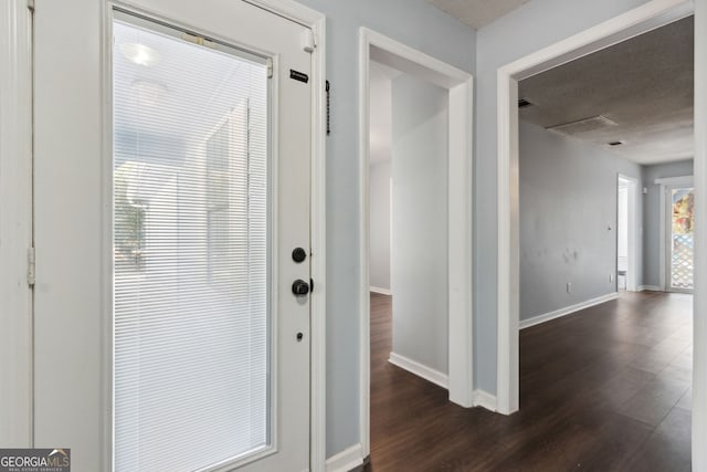 doorway to outside featuring a textured ceiling, dark wood-type flooring, visible vents, and baseboards