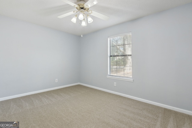 carpeted empty room featuring ceiling fan and baseboards