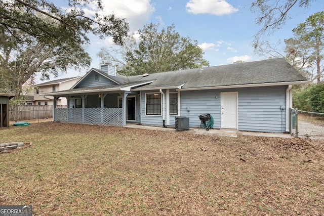 rear view of house with a chimney, roof with shingles, fence, a yard, and central AC