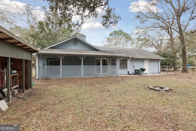 back of property with an outdoor fire pit, a chimney, fence, a yard, and central AC