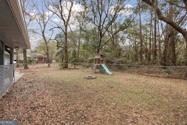 view of yard with an outdoor fire pit, a playground, and a fenced backyard