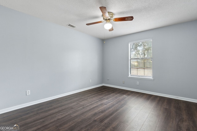 empty room featuring dark wood finished floors, visible vents, ceiling fan, a textured ceiling, and baseboards