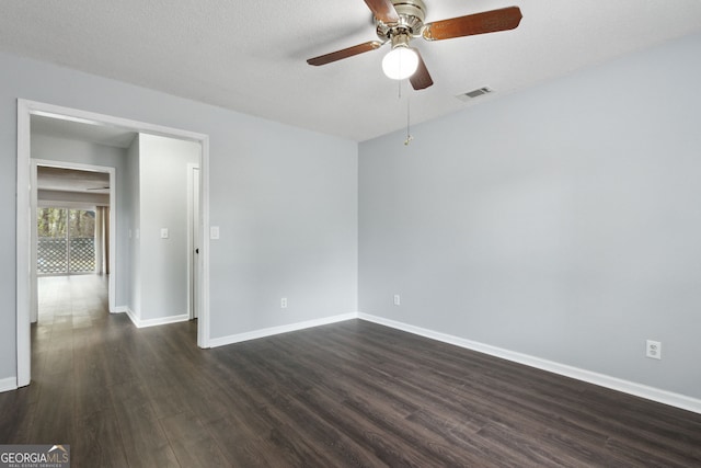 spare room featuring a textured ceiling, dark wood-style flooring, a ceiling fan, visible vents, and baseboards