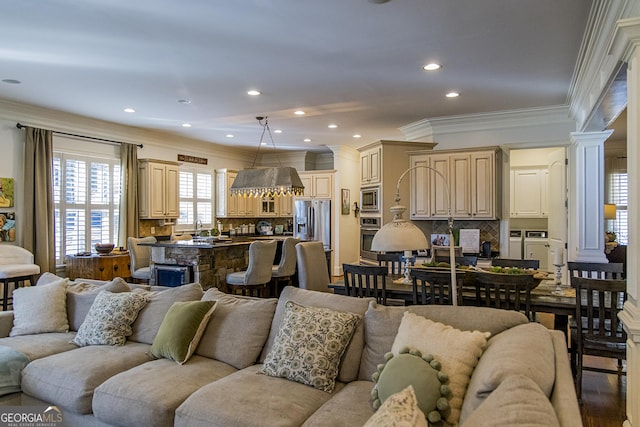 living area featuring recessed lighting, decorative columns, crown molding, and washing machine and clothes dryer