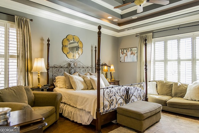 bedroom featuring ornamental molding, a raised ceiling, visible vents, and wood finished floors