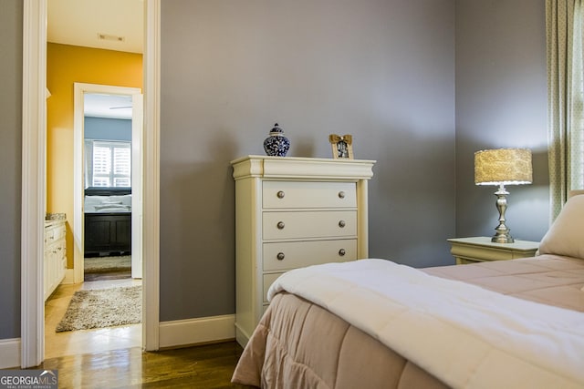 bedroom with wood finished floors, visible vents, and baseboards